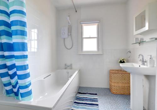 La salle de bains blanche est pourvue d'une baignoire et d'un lavabo. dans l'établissement Holbrooks House, à Robin Hood's Bay