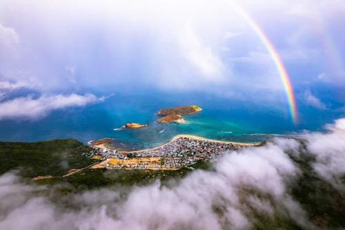 a rainbow over a small island in the ocean at NHATUIshare Quy Nhơn in Quy Nhon