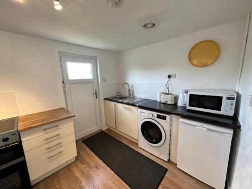 a kitchen with a washing machine and a microwave at Peninsula Cottage in Garrabost
