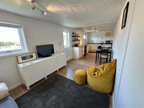 uma sala de estar com uma cadeira amarela e uma televisão em Peninsula Cottage em Garrabost