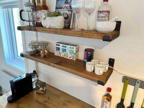 a kitchen counter with wooden shelves on the wall at Peninsula Cottage in Garrabost