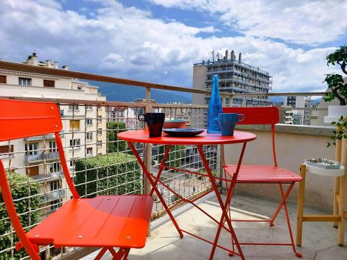 d'une table rouge et de deux chaises sur un balcon. dans l'établissement Lumineux 2 Chambres avec Garage privé - Tram à 1 min, à Grenoble