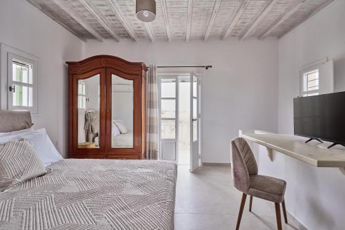 a bedroom with a bed and a desk and a television at Philippi Villa in Mýkonos City