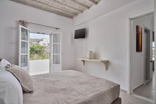 a white bedroom with a bed and a television at Philippi Villa in Mikonos