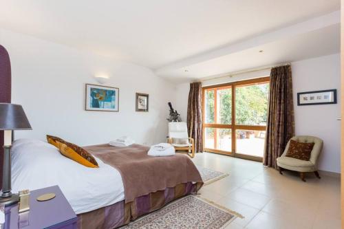 1 dormitorio con 1 cama, 1 silla y 1 ventana en Quinta Tannamara villa private pool & garden, en Burgau