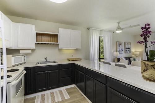 a kitchen with black cabinets and white appliances at Pono Kai H204 condo in Kapaa