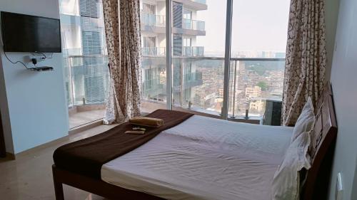 1 cama en un dormitorio con ventana grande en P N A Apartments - Manpada, en Thane