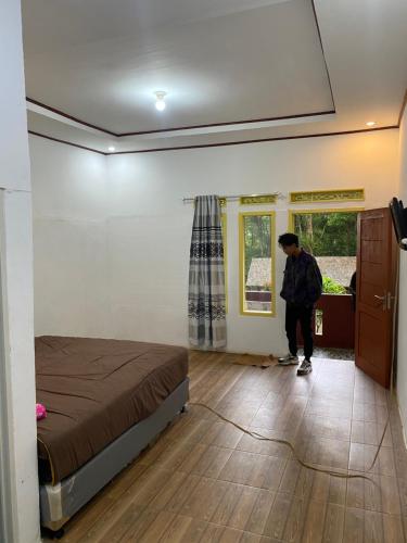 a man standing in a room with a bed at Laksana Rasa Resort Ciwidey in Ciwidey