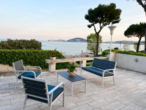 eine Terrasse mit Stühlen und einem Tisch mit Blick auf das Wasser in der Unterkunft Villa Magnolia in Formia