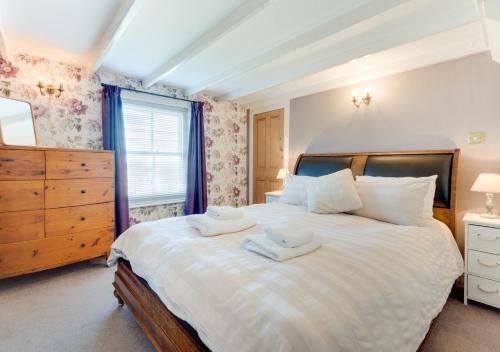 a bedroom with a large white bed with two towels on it at Hillside in Robin Hood's Bay