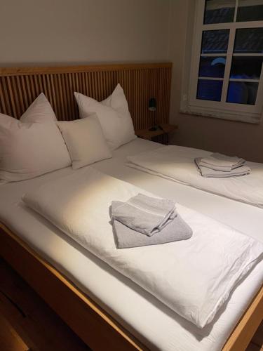 duas camas com lençóis brancos e uma toalha em Familienhaus am Meer em Dornum