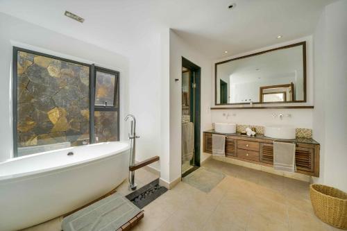 een badkamer met een bad en een grote spiegel bij Villa Ascocenda by Oazure in Bel Ombre