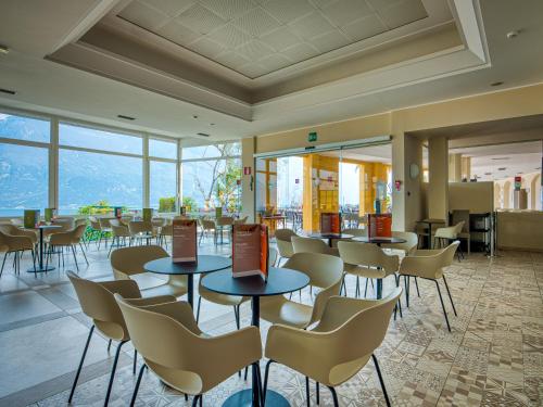 restauracja ze stołami, krzesłami i oknami w obiekcie Hotel Cristina w mieście Limone sul Garda