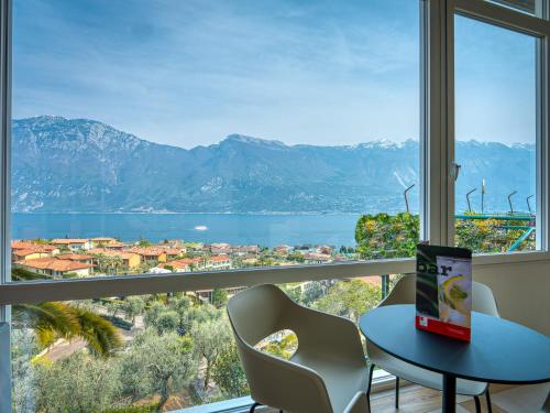 a table and chairs in front of a window with a view at Hotel Cristina in Limone sul Garda