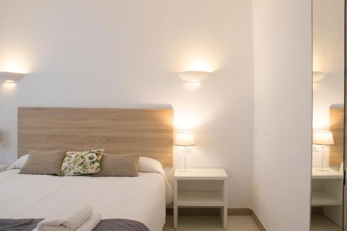 ein Schlafzimmer mit einem Bett, zwei Tischen und zwei Lampen in der Unterkunft Grupoandria Aparthotel Club Andria in Cala Santandria