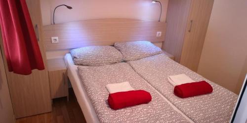 a bedroom with a bed with two red pillows on it at Camping Park Soline - Rose PB -Mobile Home in Biograd na Moru