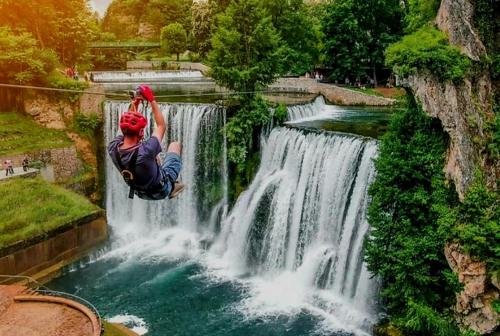 a person jumping off a waterfall into a river at Nomad Glamping in Šipovo