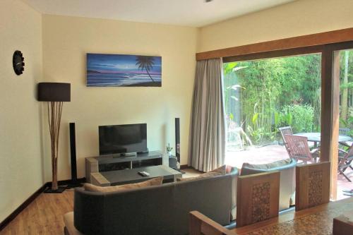 a living room with a couch and a television at Villa Asam in Kuta Lombok
