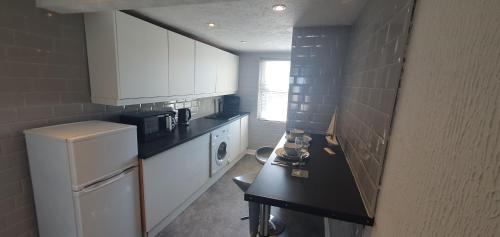 uma pequena cozinha com armários brancos e um frigorífico em Ocean View em Llandrillo-yn-Rhôs