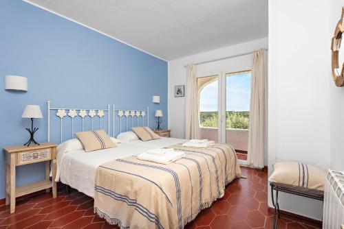 two beds in a room with a window at Villa Ponte - Cala Galdana in Cala Galdana
