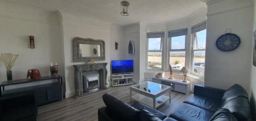 a living room with a blue couch and a fireplace at Ocean View in Llandrillo-yn-Rhôs
