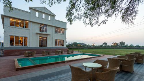 a house with a swimming pool and tables and chairs at The Arowana Divine in Nānded