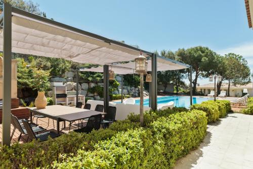 een tafel en stoelen onder een luifel naast een zwembad bij Luxury Seaview Villa by Olala Homes in Teià