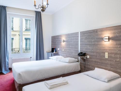 Cette chambre comprend 2 lits et une fenêtre. dans l'établissement Hôtel du Helder, à Lyon
