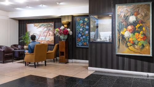 a man sitting at a table in a waiting room at Hôtel du Helder in Lyon