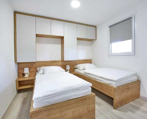 two beds in a room with white walls and a window at Mobile Homes Terme Jezercica in Donja Stubica