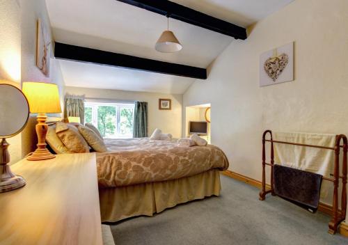 a bedroom with a bed and a window at Foss Garth Cottage in Thwaite
