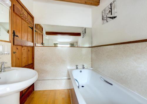 a bathroom with a tub and a sink and a bath tub at Foss Garth Cottage in Thwaite