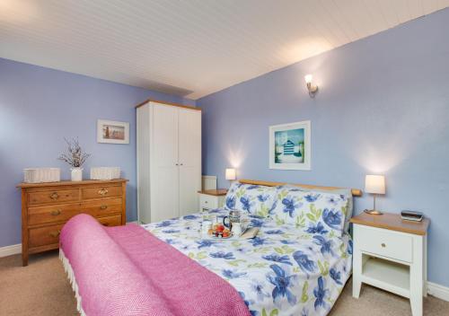 a bedroom with blue walls and a bed with a pink blanket at Flat 4 Whitehaven in Sandsend