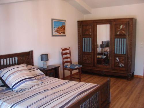 1 dormitorio con cama, silla y espejo en Gites Le Grand Jardin, en Puydarrieux