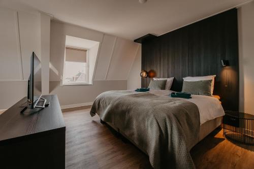 a bedroom with a large bed and a flat screen tv at Residence Oude Haven Colijnsplaat appartementen met verdieping in Colijnsplaat