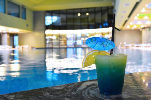 a drink sitting on a table next to a swimming pool at Hotel Piatra Mare in Poiana Brasov