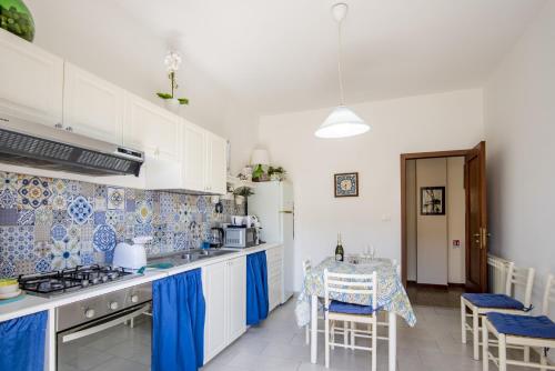 a kitchen with white cabinets and blue and white tiles at Etna Sicilian House in Linguaglossa