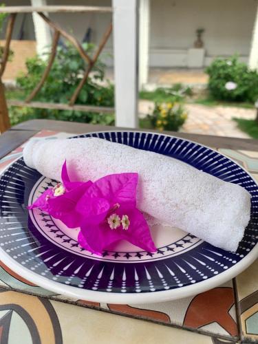 a purple flower on a plate with a towel at Pousada da Renata in Jericoacoara