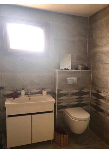 baño con aseo y lavabo y ventana en Ala din, en Bel Aroussi