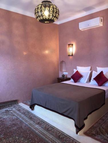Un dormitorio con una cama grande y una lámpara de araña. en Ala din, en Bel Aroussi