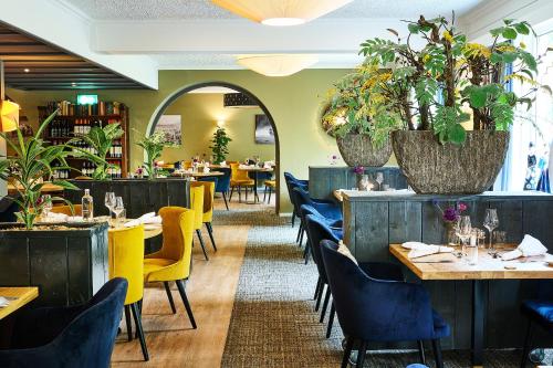 a restaurant with tables and chairs and plants at Hotel 't Kruisselt in De Lutte