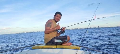 a man sitting on a boat holding a fishing rod at โอบกอด รีสอร์ท เกาะล้าน in Ko Larn