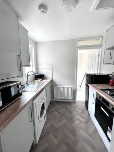 a kitchen with white cabinets and a washer at 3 Bedroom spacious Flat in Gateshead