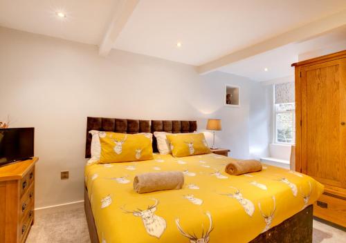a bedroom with a yellow bed with deer heads on it at Eta Cottage in Kettlewell