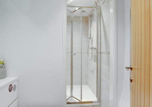 a shower with a glass door in a bathroom at Eta Cottage in Kettlewell