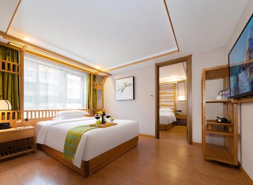 um quarto com uma grande cama branca e uma televisão em Xiangxi's Lovely - Yangyun Hotel em Zhangjiajie