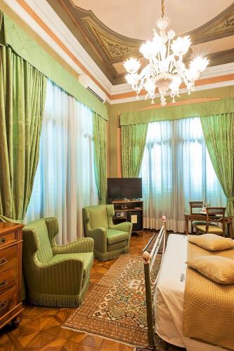 a bedroom with a bed and chairs and a chandelier at Villa Ducale Hotel & Ristorante in Dolo