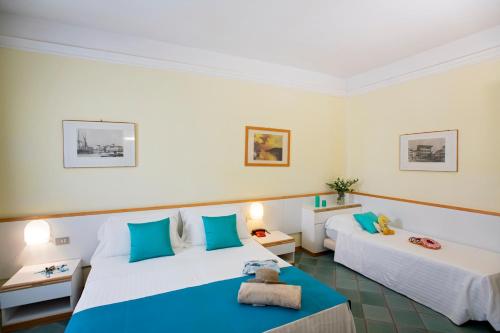 Habitación de hotel con 2 camas y almohadas azules en Cav Approdo, en Castiglione della Pescaia