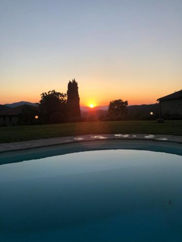 a sunset over a swimming pool with the sun setting at Resort con vista nel Chianti Rufina in Londa