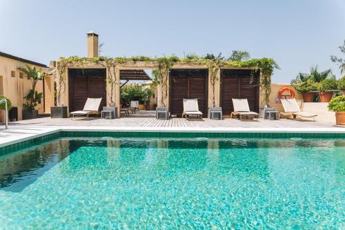 a swimming pool with chairs and a house at Rio Real Golf Hotel in Marbella